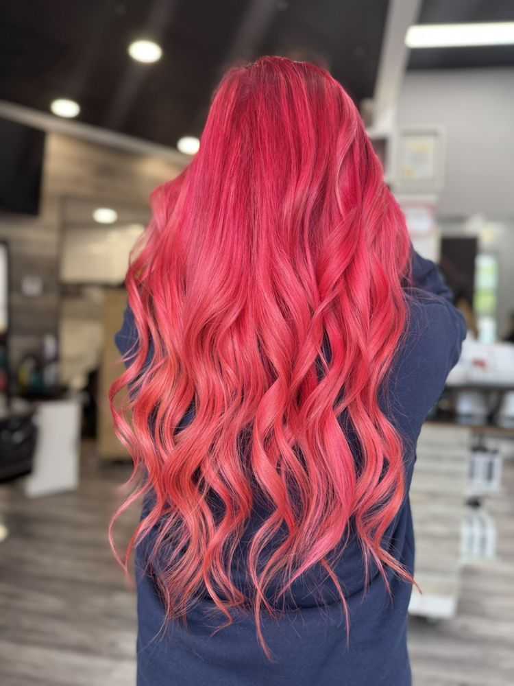 Long vibrant pink wavy hair cascading down a person's back in a salon setting.